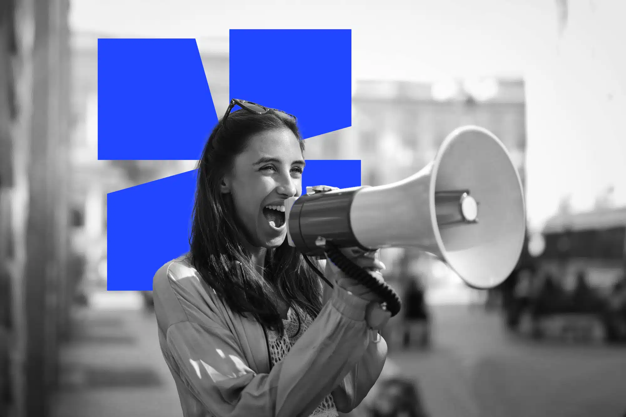 A photo in black and white of a smiling young lady shouting in a megaphone, with a blue icon on background